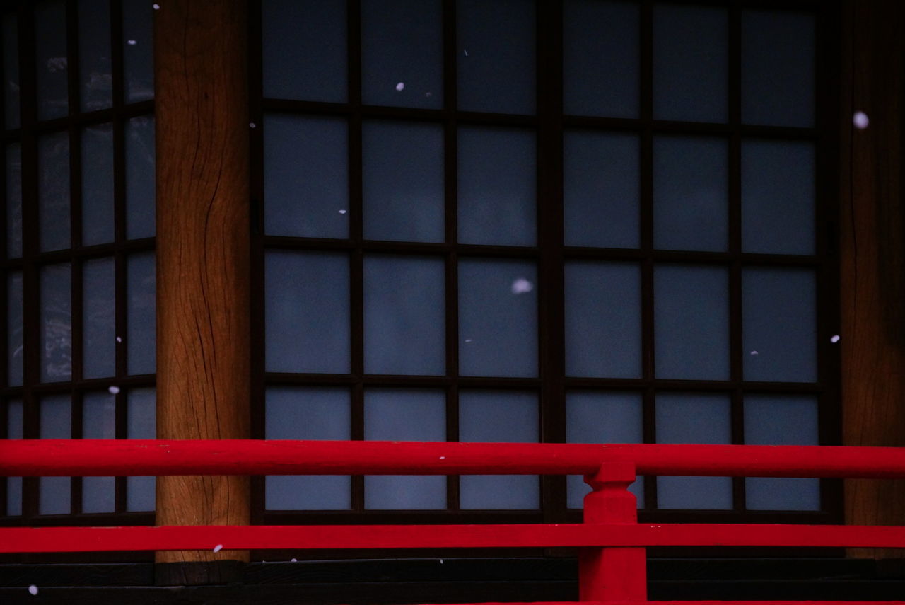 Red railing against temple during snowfall