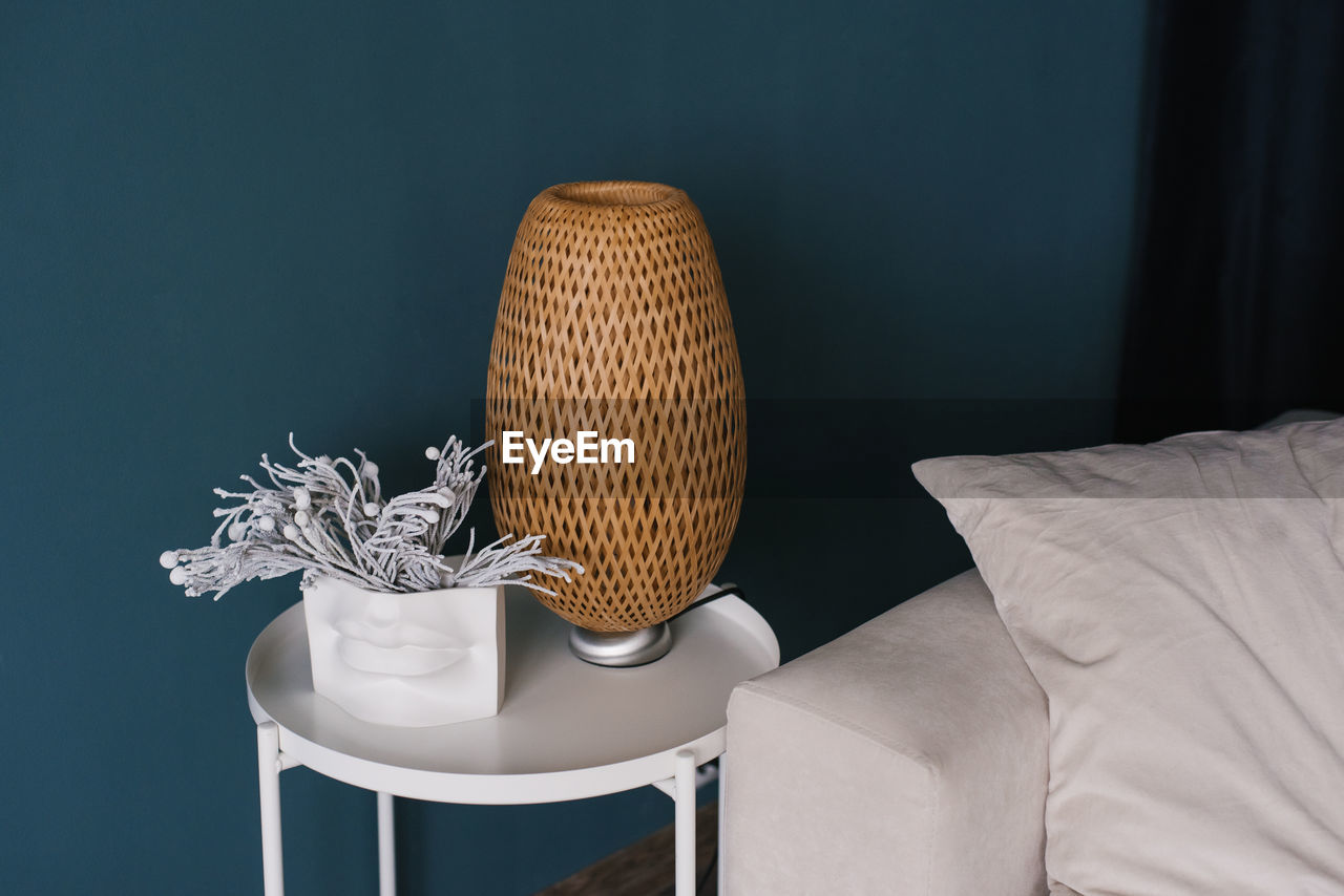 Wicker lamp on the coffee table near the white sofa in the modern living room of the house