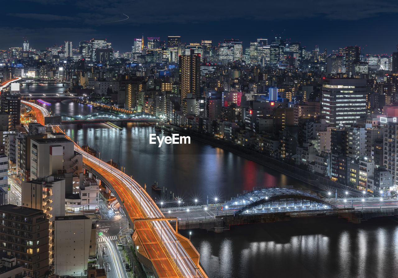 Aerial night view of the sumida river bridges and higways light-up with the skyscrapers of tokyo.