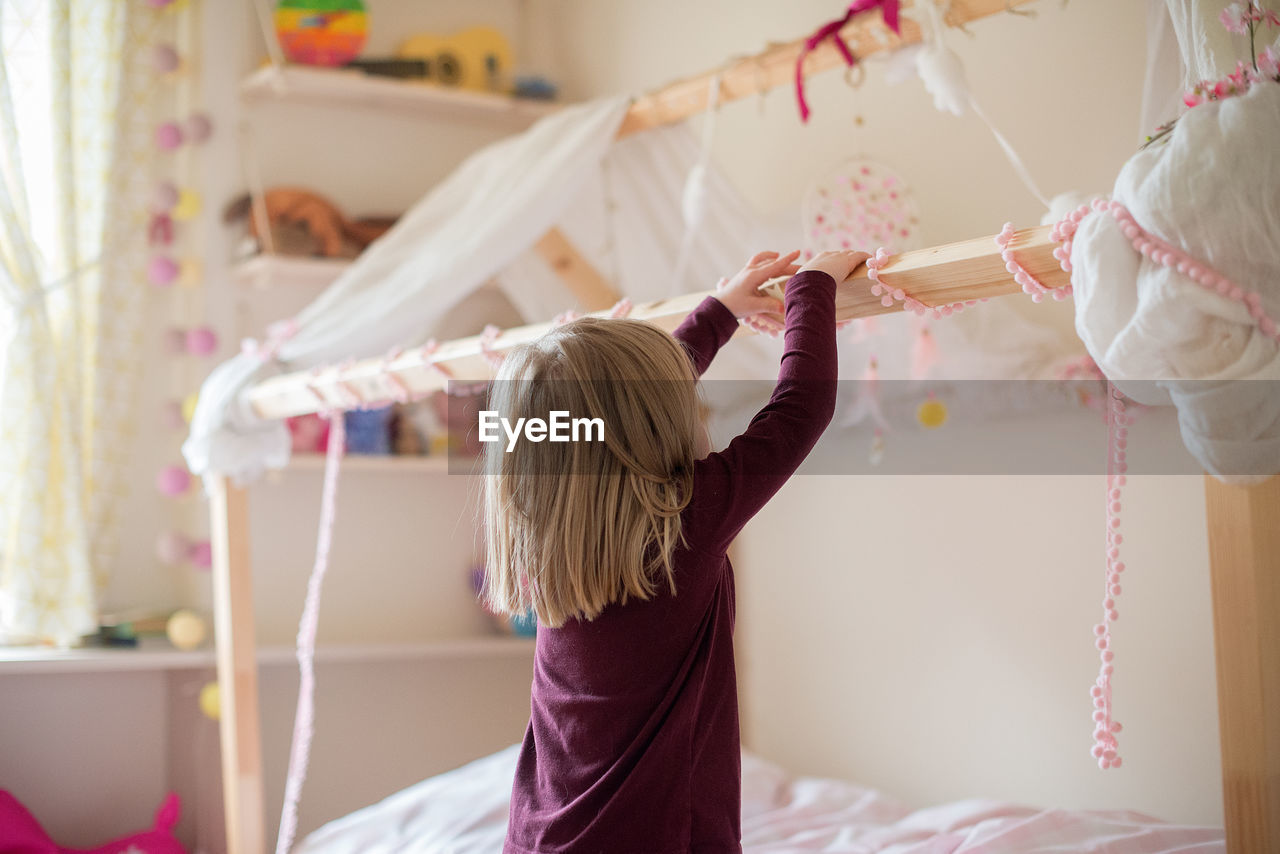 Rear view of girl playing with lace at home