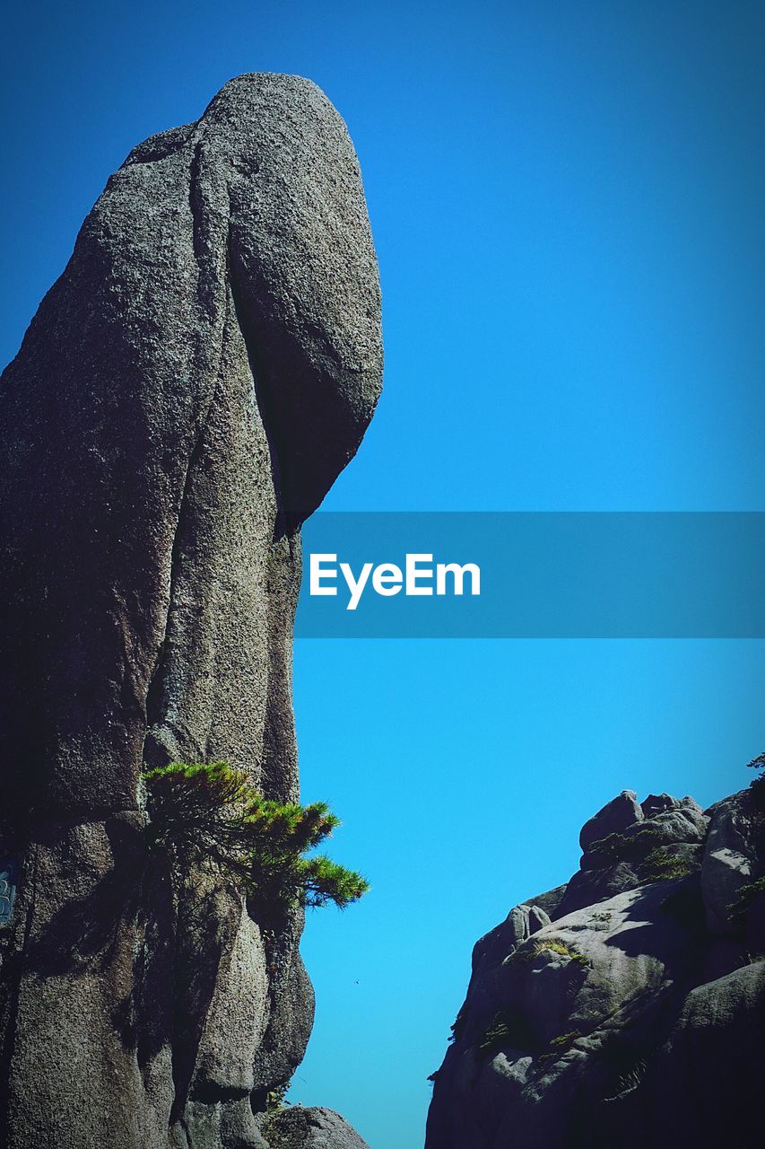 LOW ANGLE VIEW OF CLIFFS AGAINST CLEAR BLUE SKY