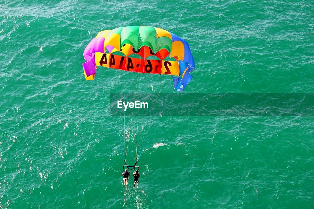 High angle view of people paragliding over sea