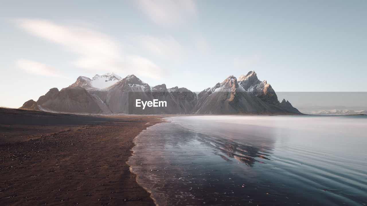 Scenic view of sea and mountains against sky