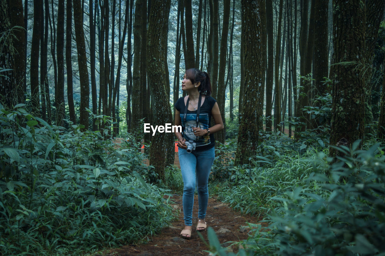 Full length of asian woman walking in forest