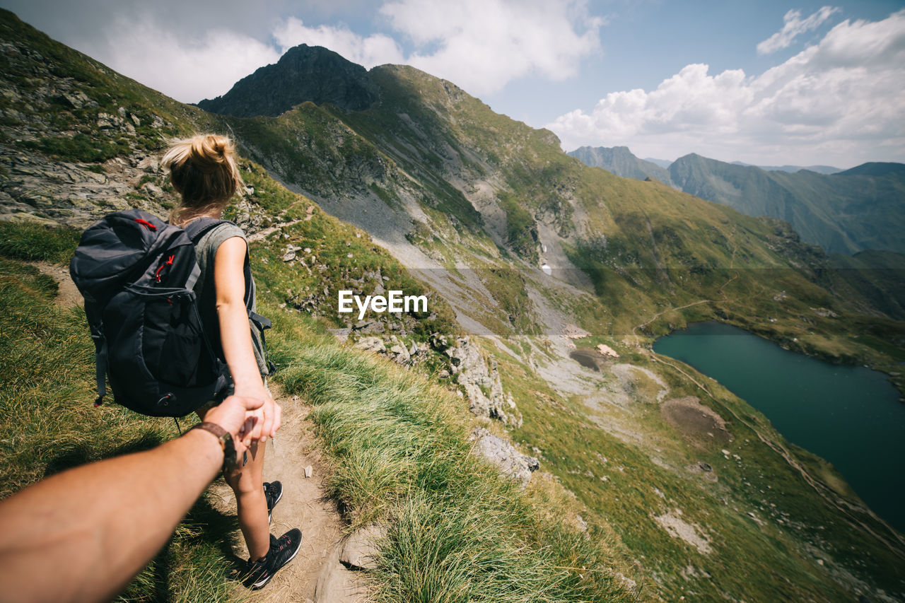 Cropped hand holding woman on mountain