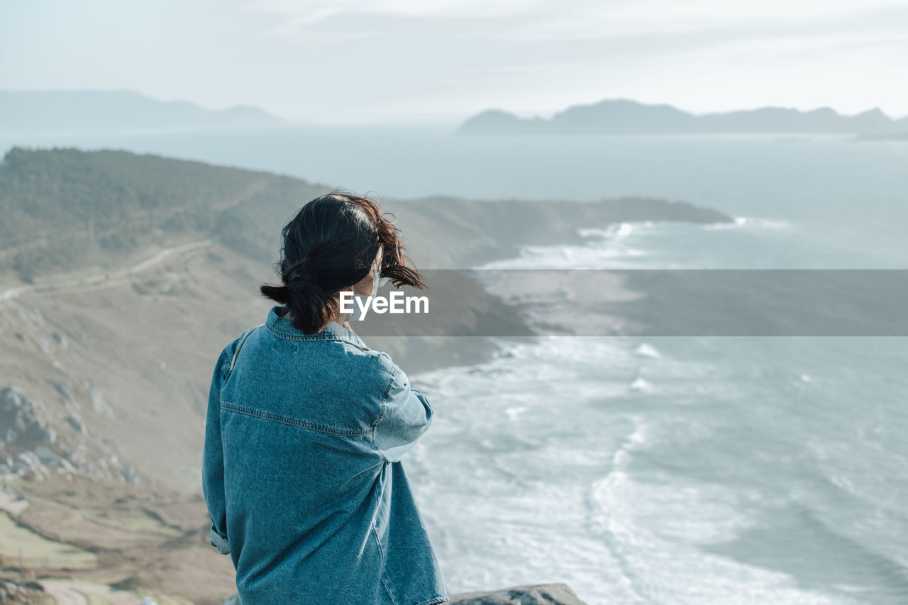 Rear view of young woman looking at sea