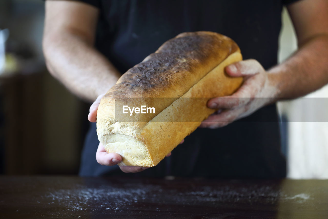 Midsection of man holding bread