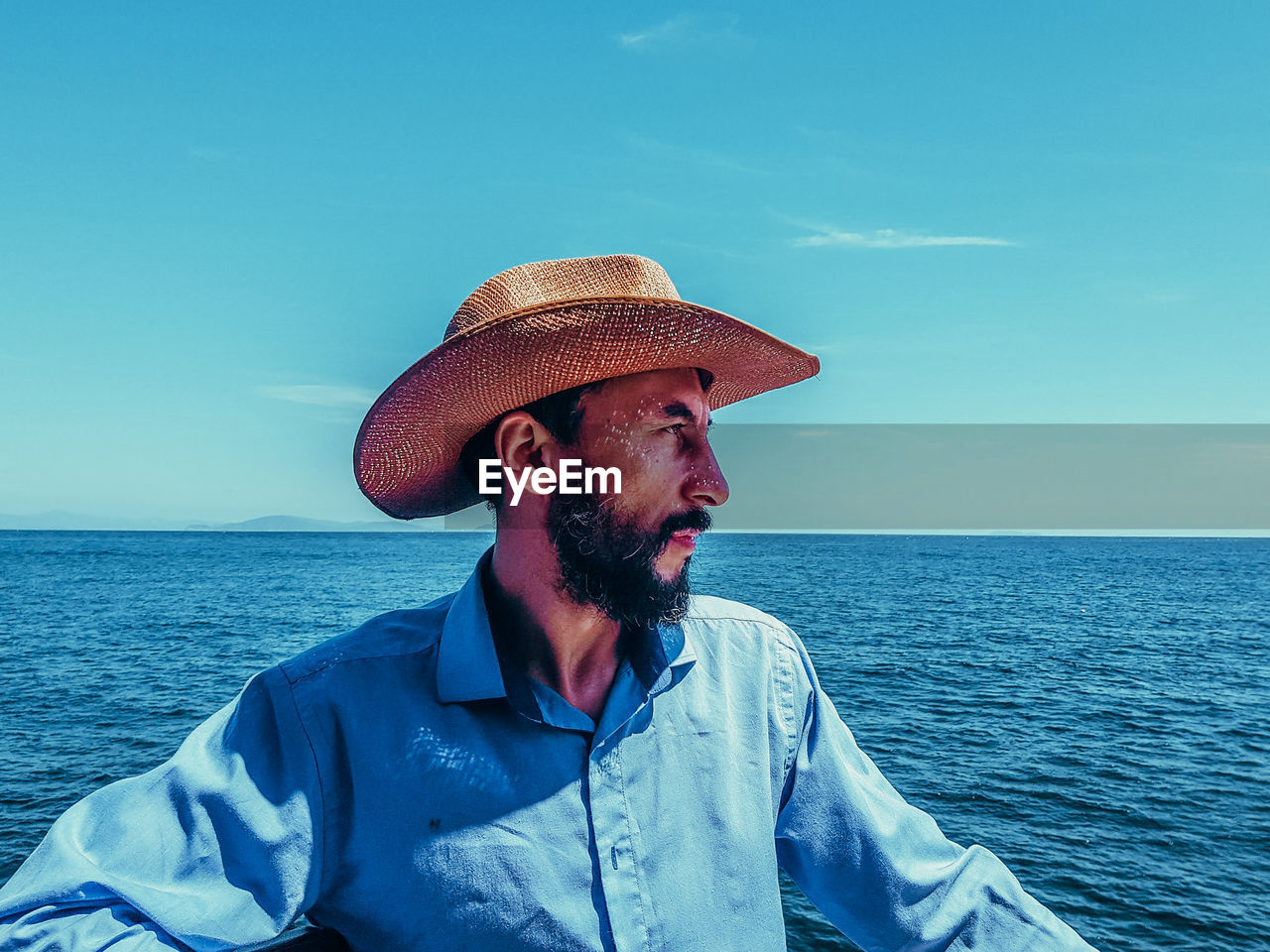 Man wearing hat while looking at sea against sky