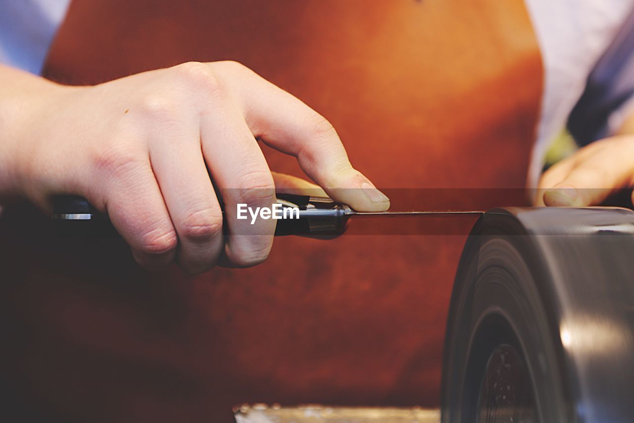 Cropped image of hand sharpening knife