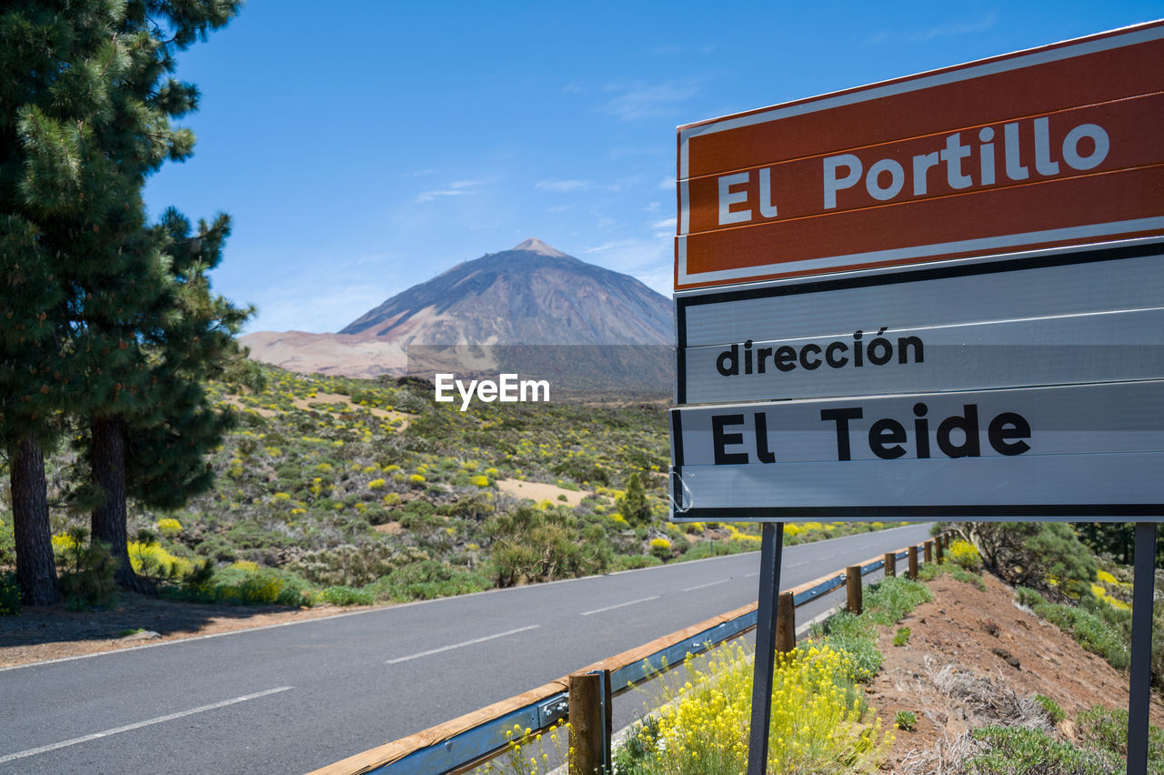 sign, road, communication, text, mountain, road trip, western script, nature, road sign, highway, transportation, sky, symbol, no people, guidance, lane, travel, plant, landscape, scenics - nature, travel destinations, tree, blue, information sign, directional sign, infrastructure, freeway, day, beauty in nature, outdoors, tourism, environment, land, city, traffic sign, arrow symbol, signage, mountain pass, mountain range, cloud, trail, street