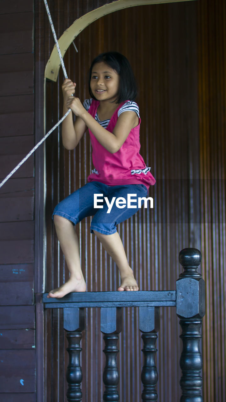 Smiling girl hanging on rope