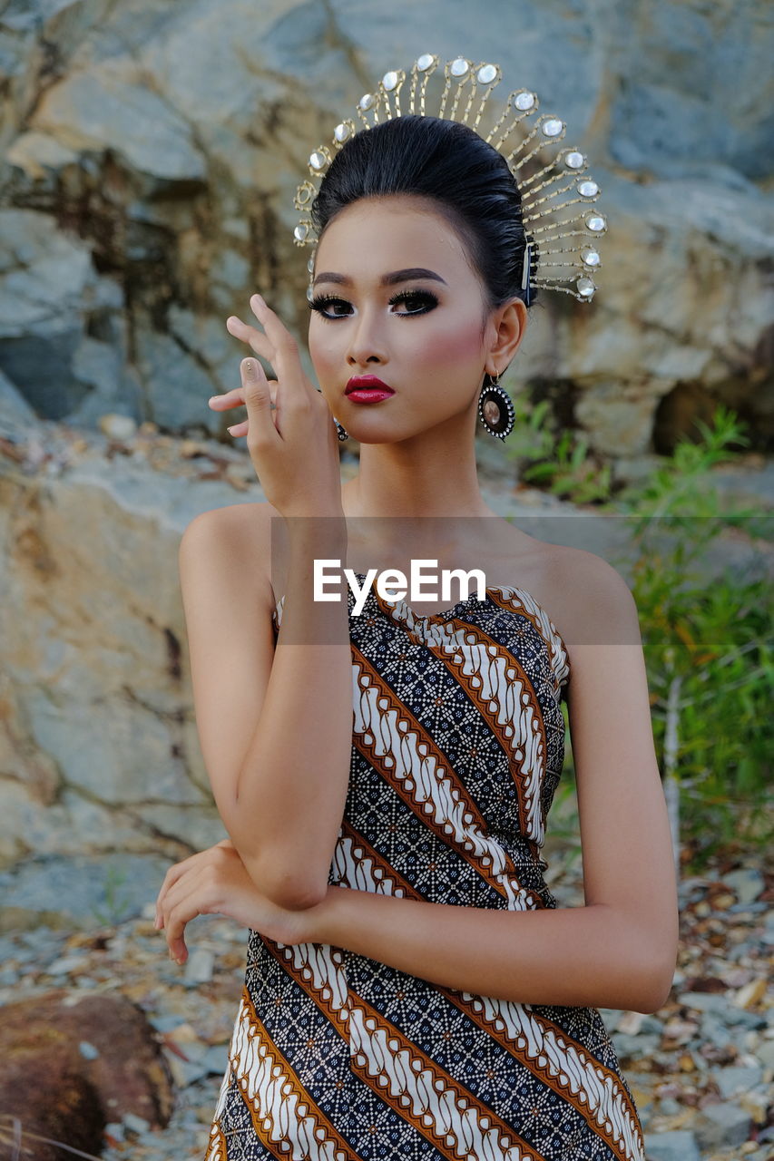 Portrait of woman gesturing while standing against rock