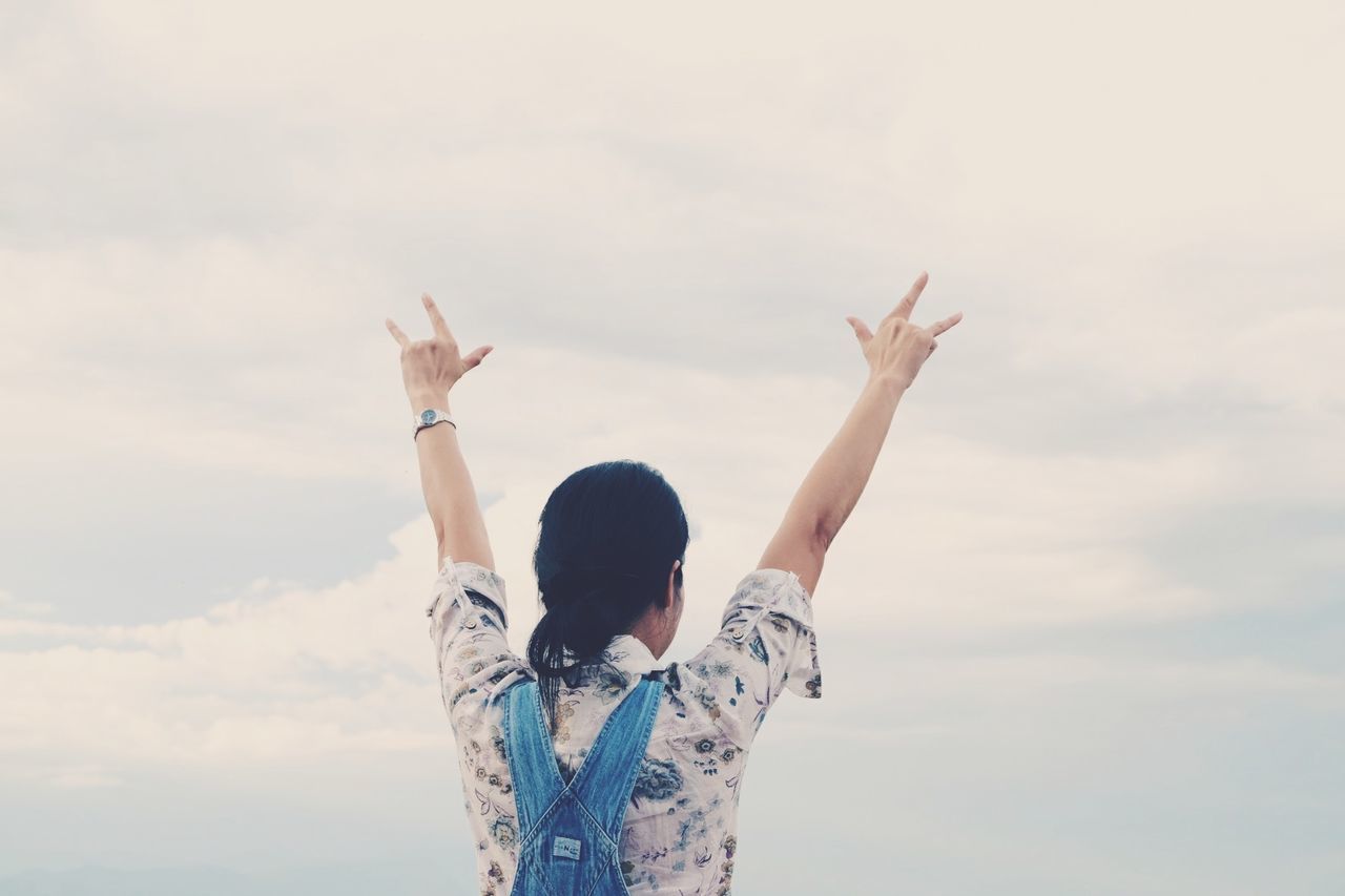 Woman with arms raised against sky