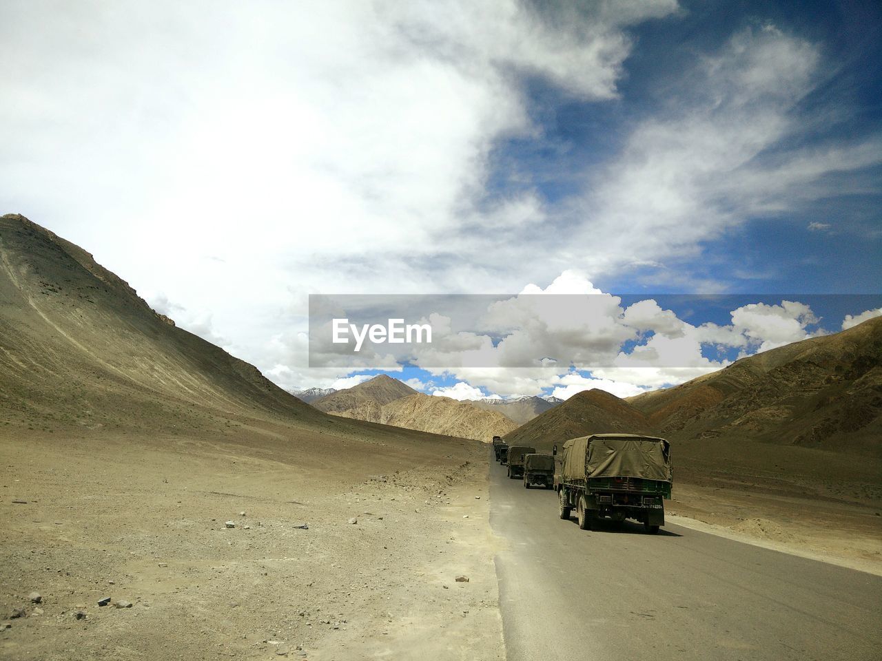 Military trucks on mountain road against sky