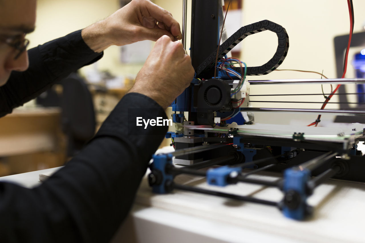 Male engineer fixing 3d printer on table