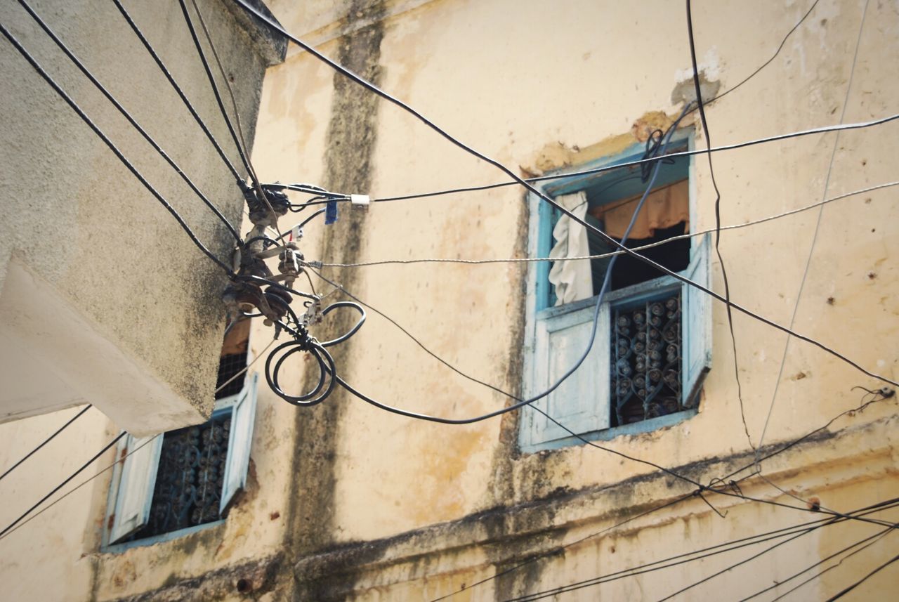 Low angle view of power lines against building