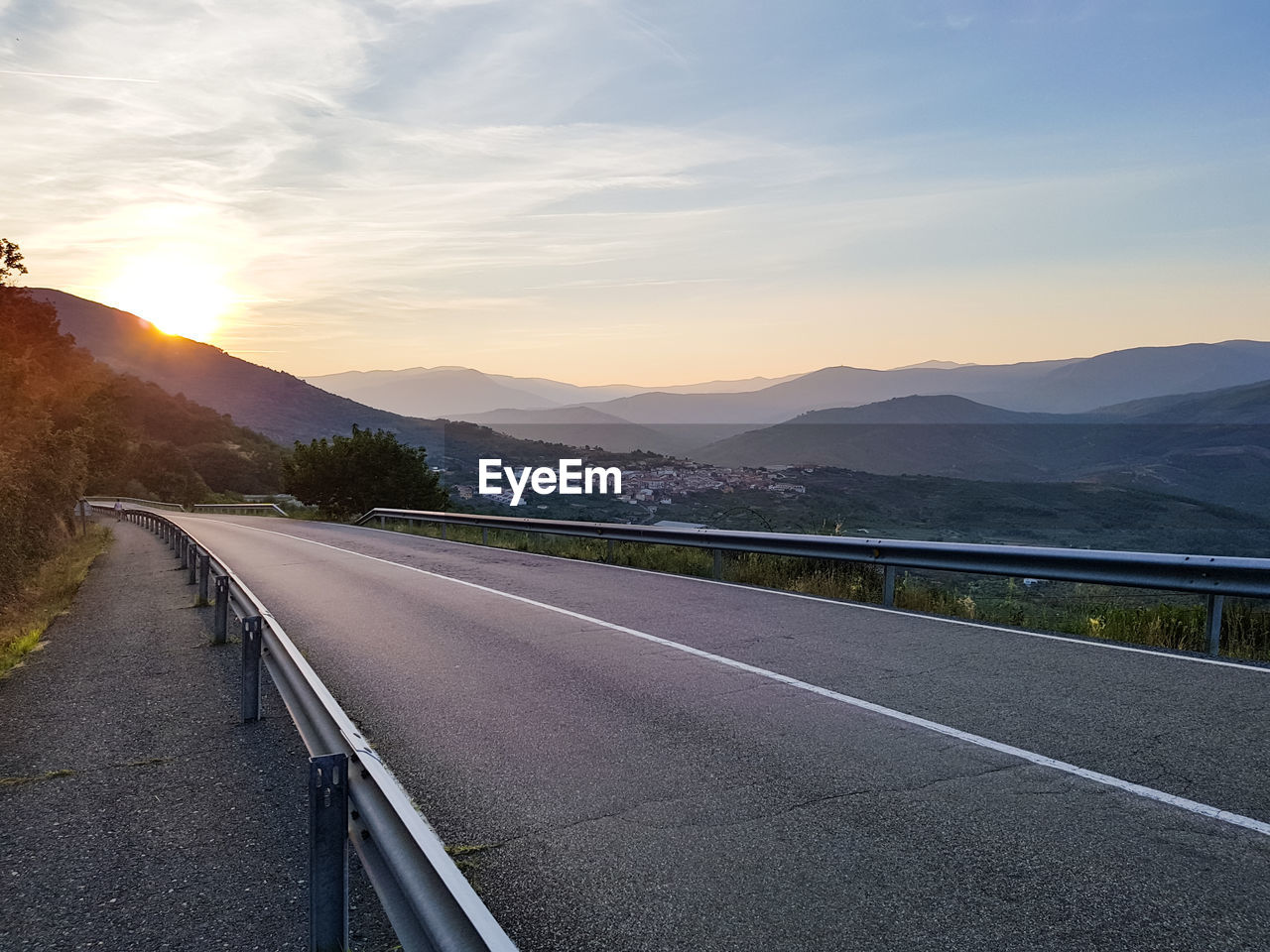 Road by mountains against sky during sunset