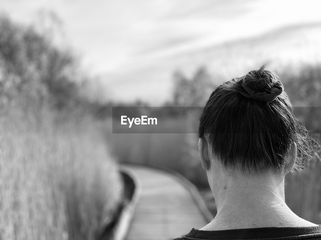 Black and white monochrome rear view of woman walking on a boardwalk