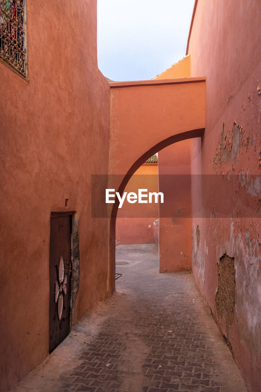 Passage with houses and orange walls in historic medina in marrakech