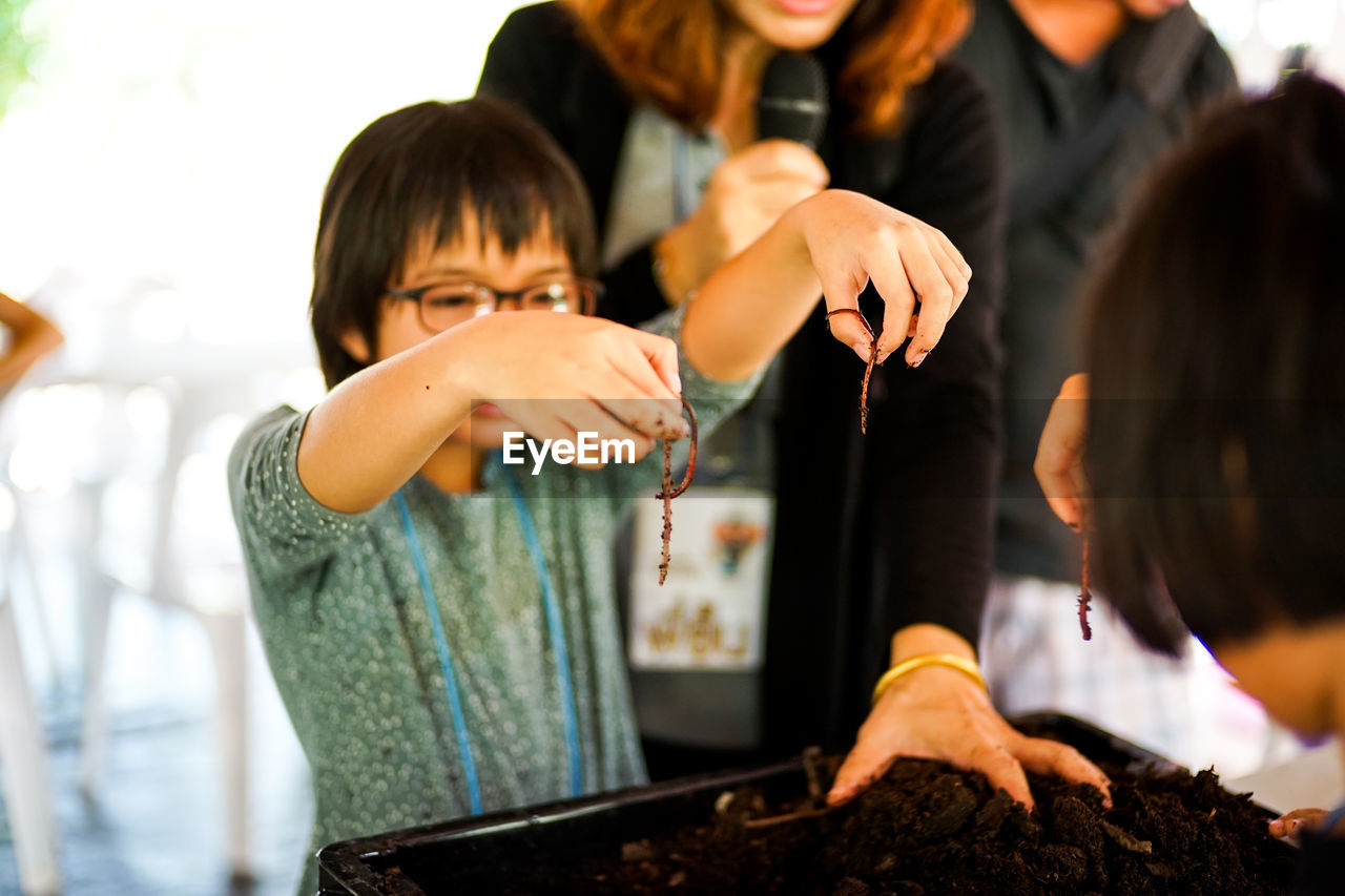 Girl holding earthworms over container