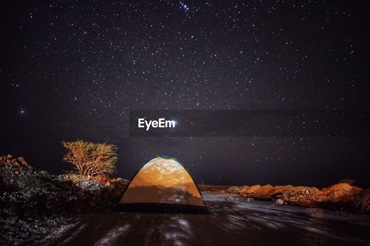 Tent on land against star field at night