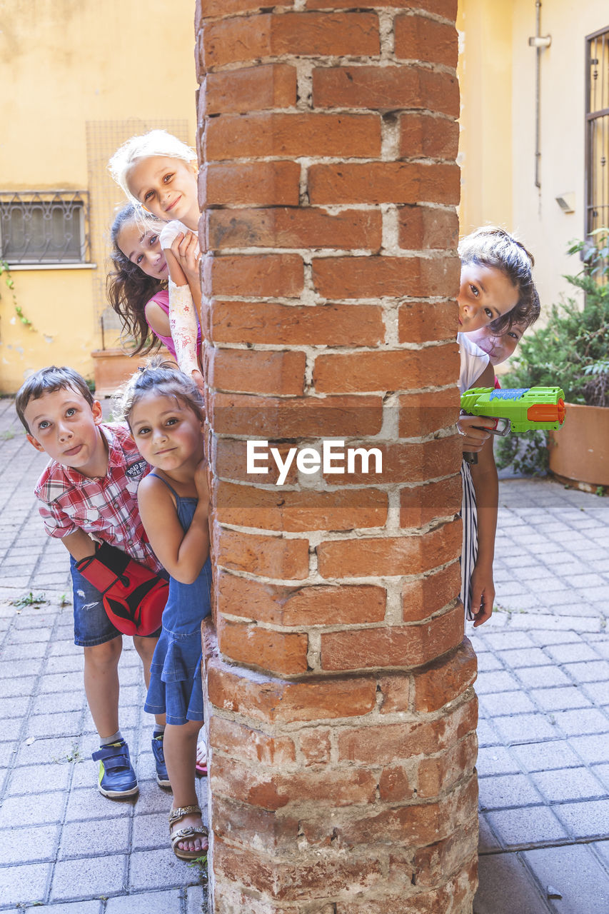 Group of little boys of different ages having fun and playing together in a courtyard