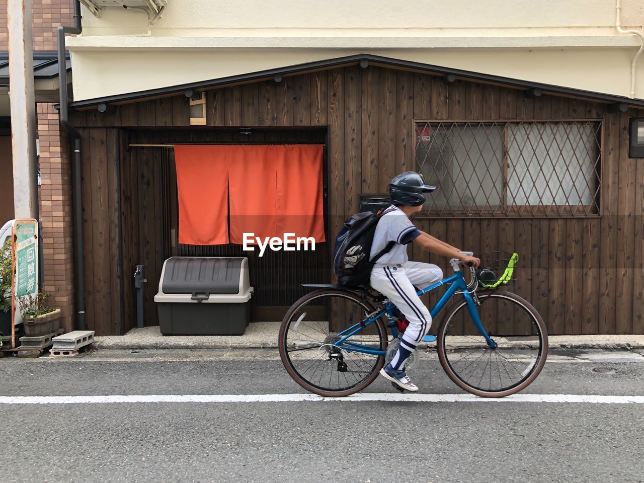 MAN RIDING BICYCLE ON STREET AGAINST BUILDING