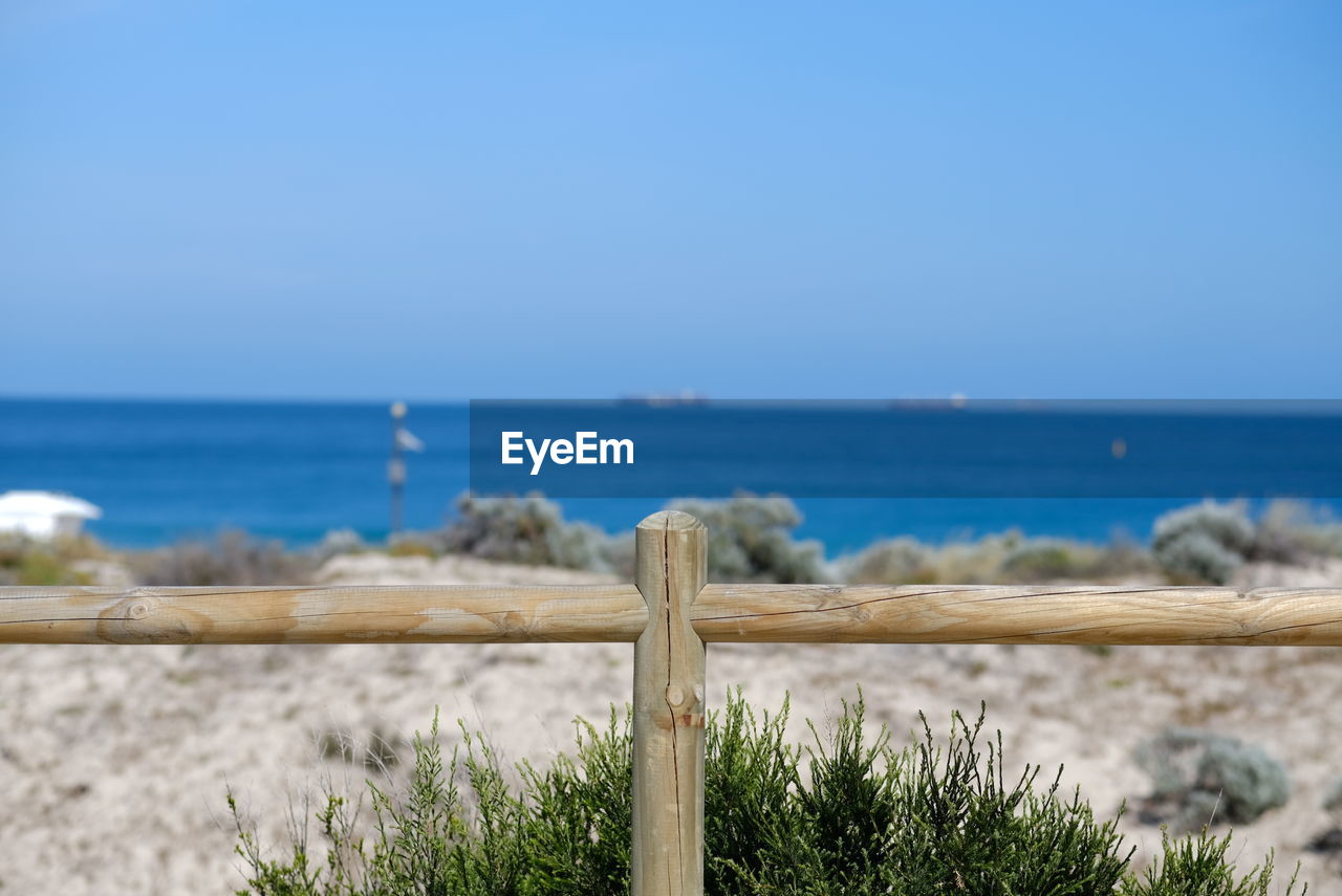 SCENIC VIEW OF SEA AGAINST CLEAR SKY SEEN THROUGH WOODEN POST