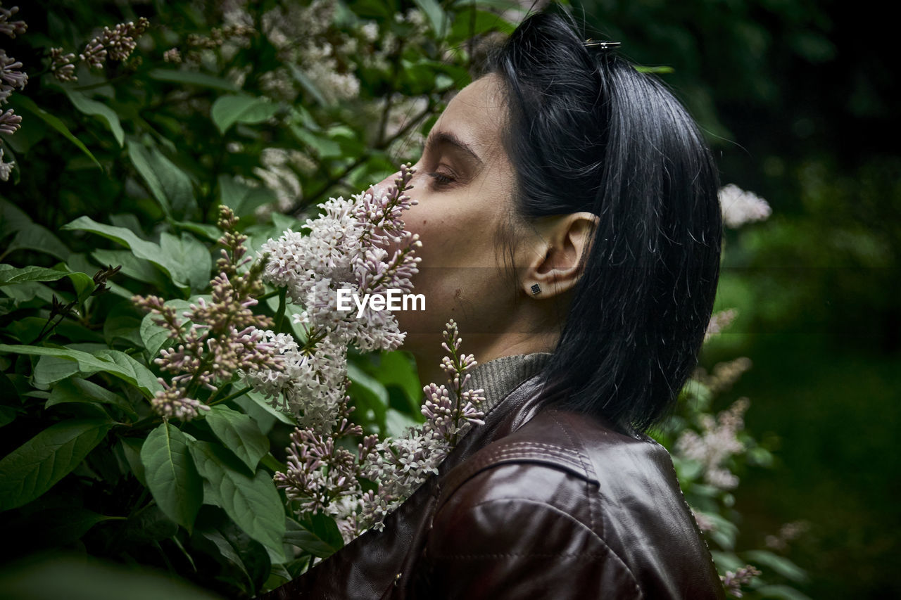 Portrait of young woman looking at flowering plants