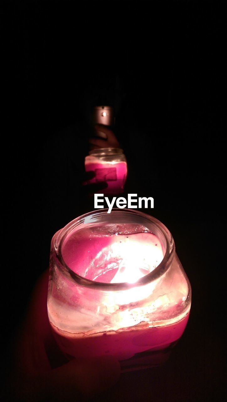 Close-up of illuminated candle over black background