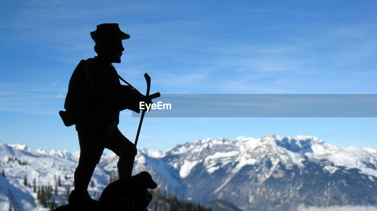 Silhouette figurine by snow covered mountains against sky