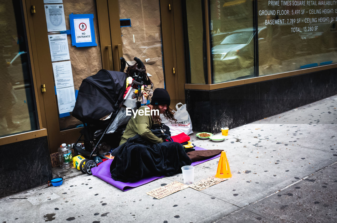 PEOPLE SITTING ON GARBAGE AGAINST WINDOW