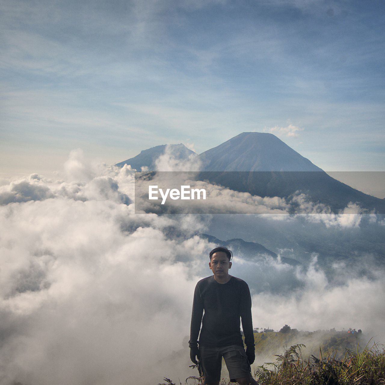 MAN STANDING ON MOUNTAINS AGAINST SKY