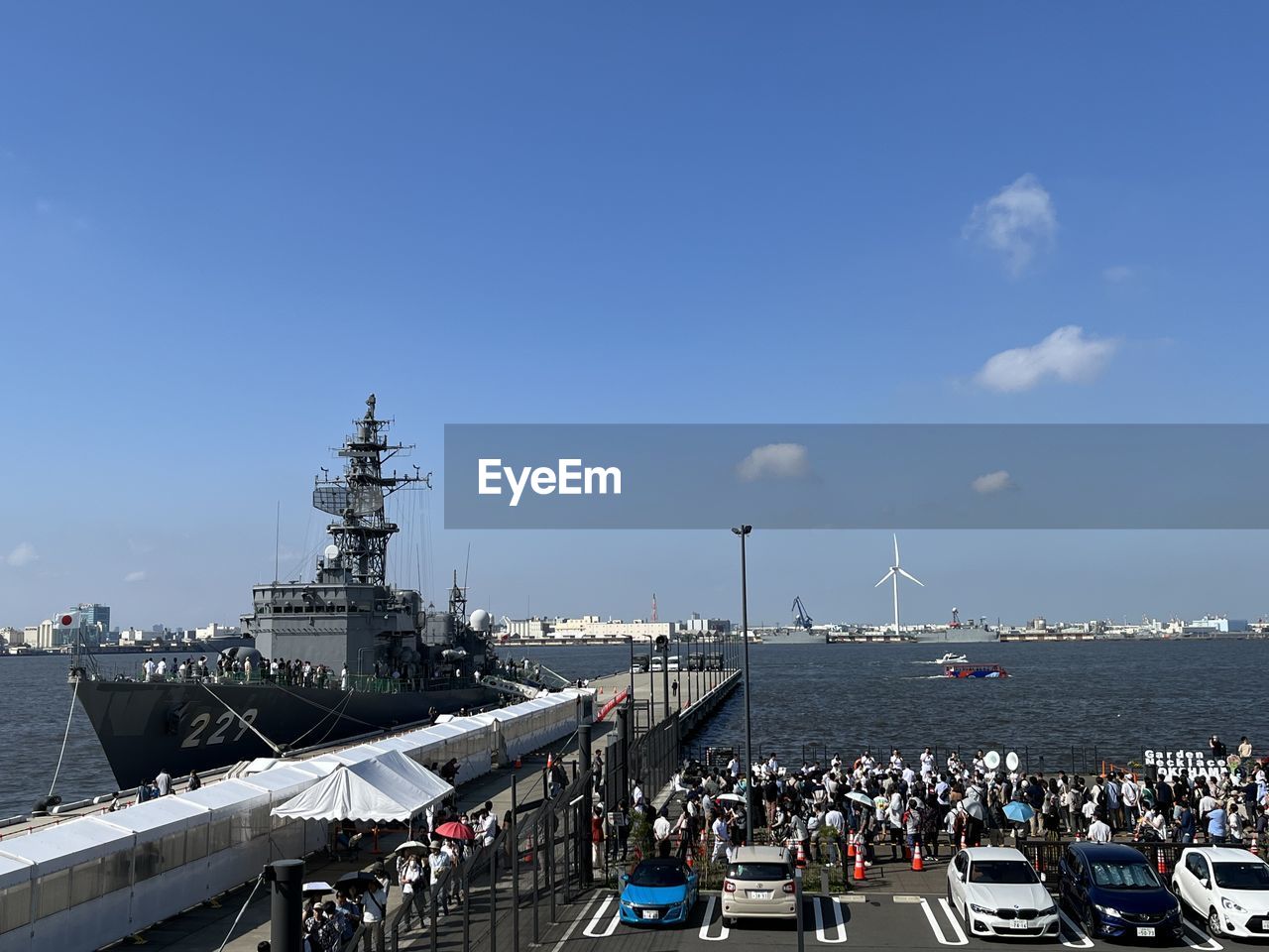 warship, transportation, vehicle, sky, naval ship, ship, mode of transportation, architecture, navy, nautical vessel, water, aircraft carrier, destroyer, sea, nature, built structure, large group of people, watercraft, travel, crowd, city, battleship, travel destinations, guided missile destroyer, day, outdoors, harbor, building exterior, group of people, blue, frigate, cloud, tourism