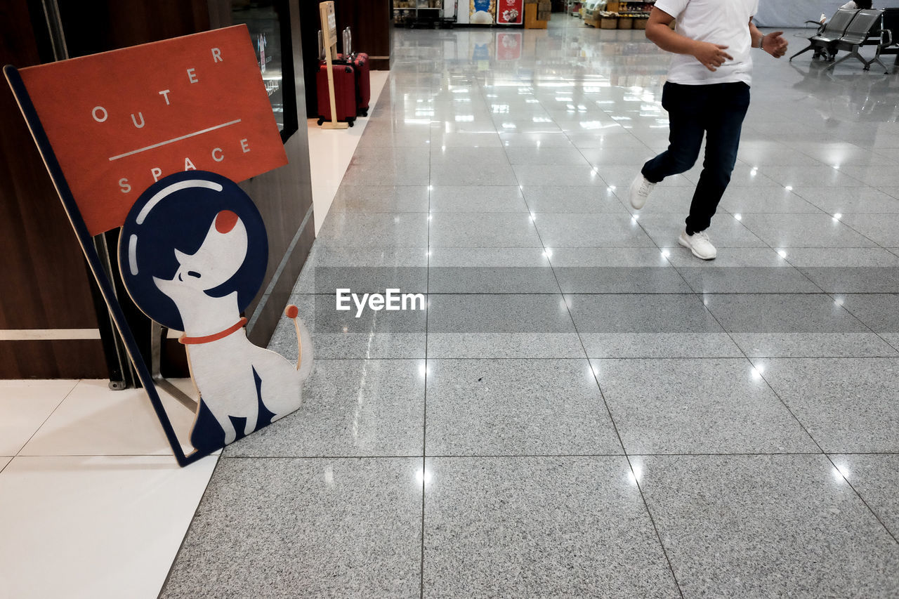 LOW SECTION OF MAN WALKING BY TILED FLOOR