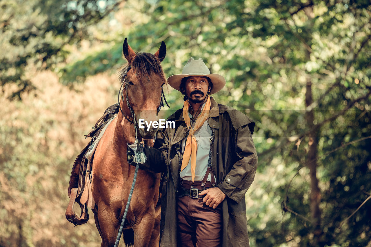 Cowboy with horse standing in forest