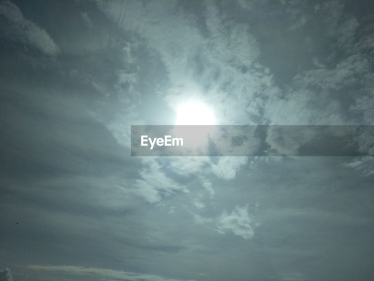 LOW ANGLE VIEW OF SUN SHINING ON CLOUDY SKY