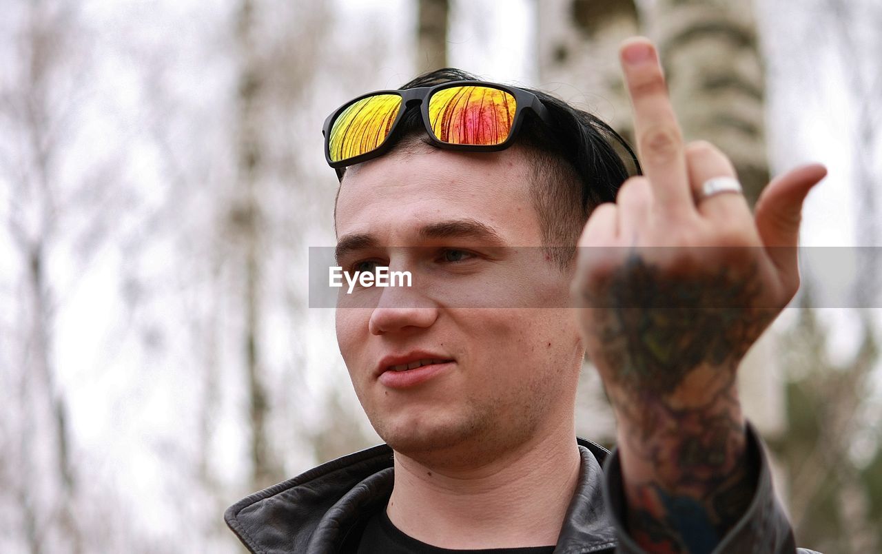Young man with sunglasses showing obscene gesture