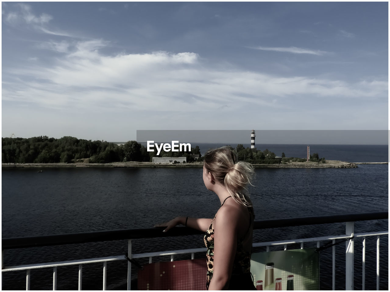 Teenage girl looking away while standing by railing