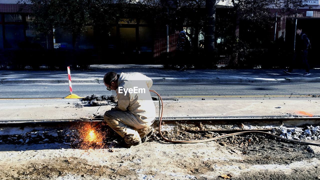 Construction worker welding on road