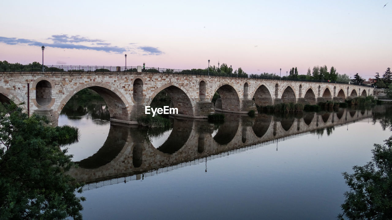 Arch bridge over river against sky