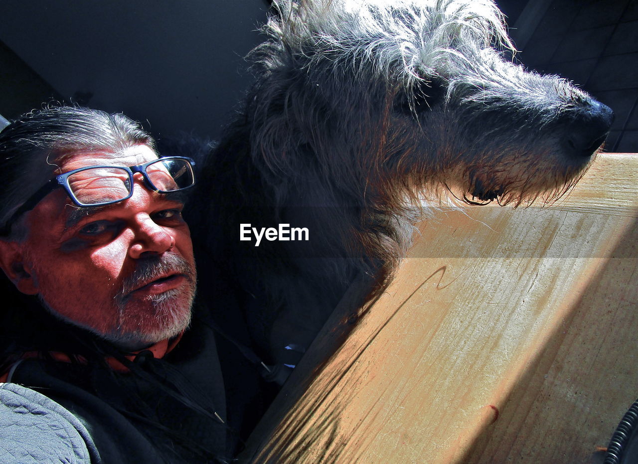 CLOSE-UP PORTRAIT OF MAN WITH DOG AT HOME