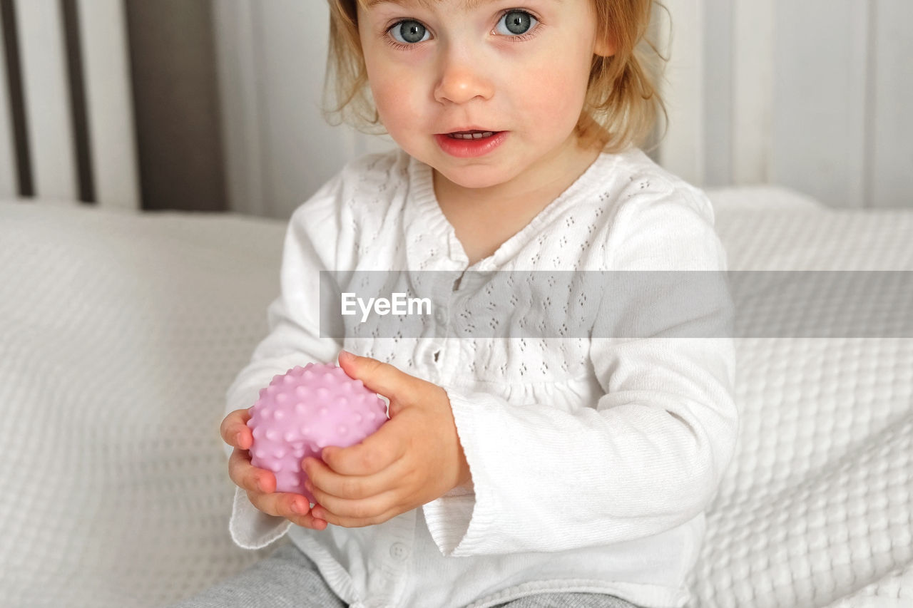 Baby girl playing tactile knobby balls. young child hand plays sensory massage ball