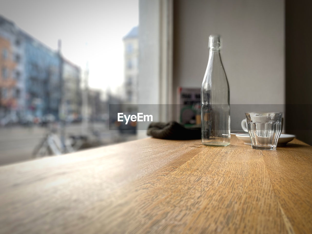 table, floor, flooring, drink, food and drink, glass, no people, drinking glass, refreshment, day, indoors, container, architecture, bottle, nature, wood, household equipment, business, window, absence, water, room, alcohol, focus on foreground, city, empty, surface level