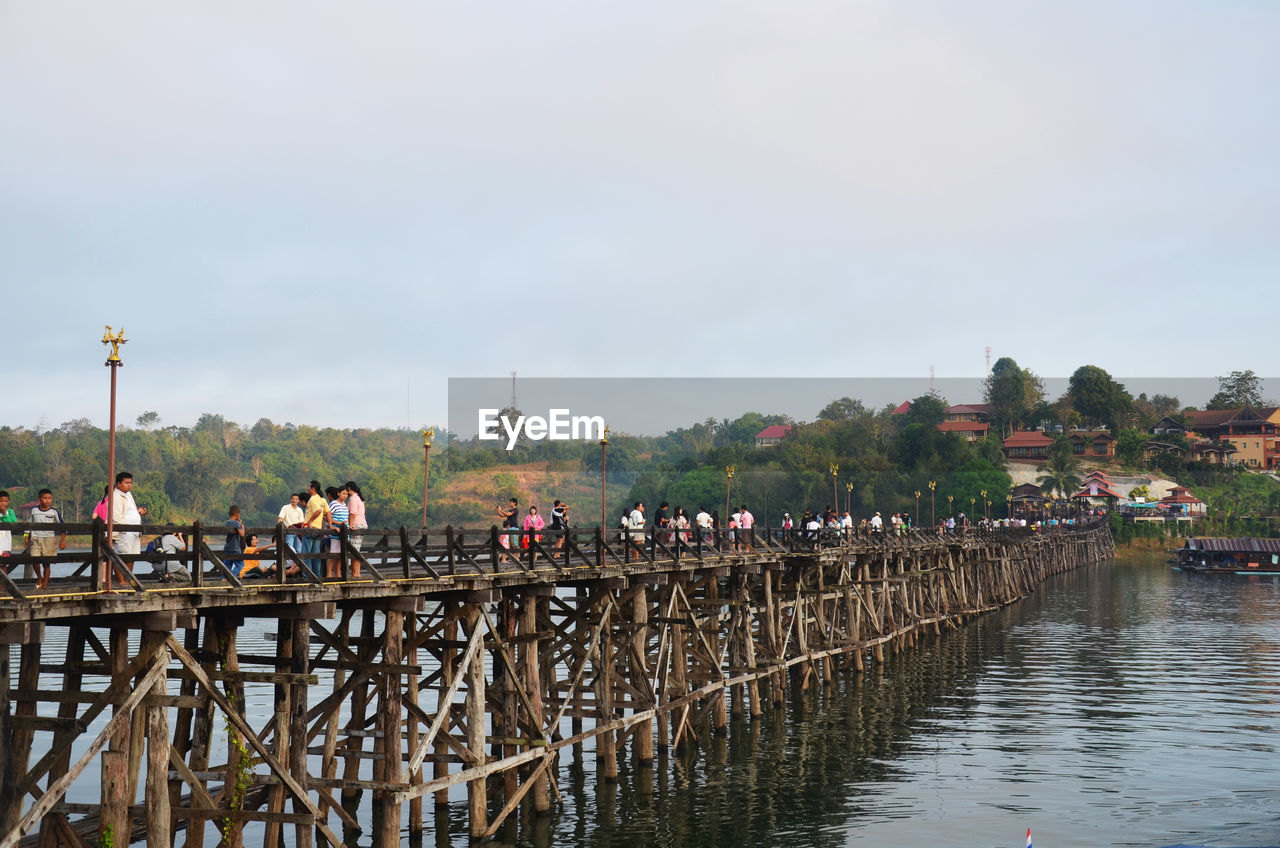 GROUP OF PEOPLE ON BRIDGE OVER RIVER