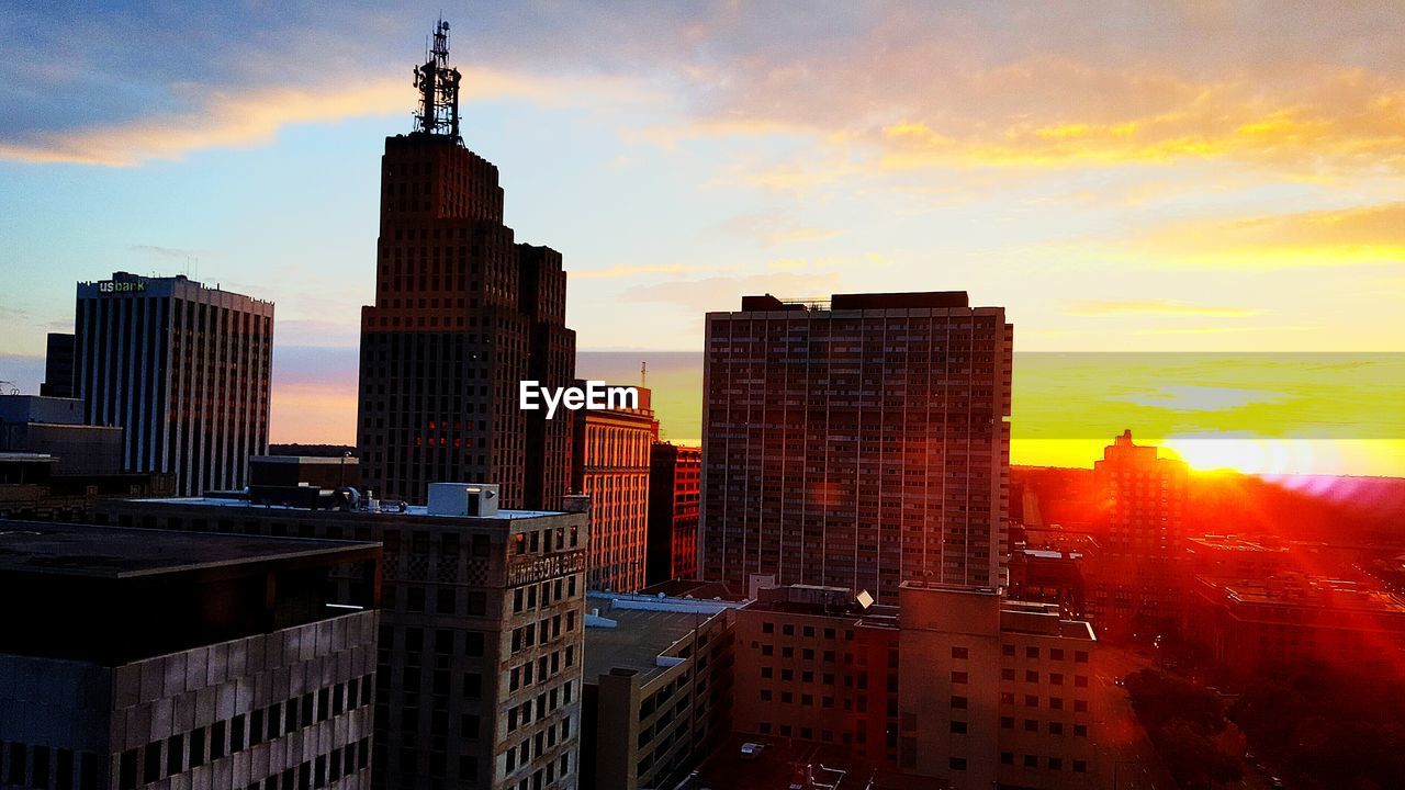 Buildings against sky during sunrise in city