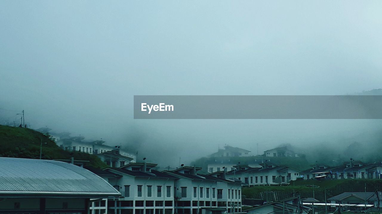 Houses and buildings in city against sky