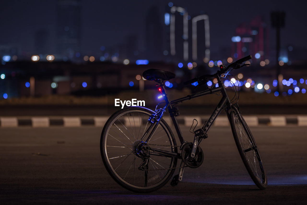 BICYCLE PARKED ON ILLUMINATED STREET