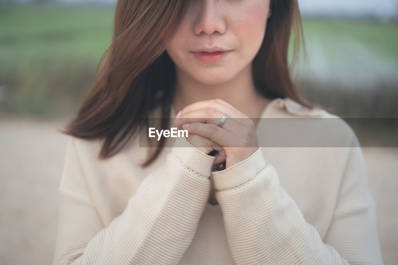 Midsection of beautiful young woman with hands clasped praying