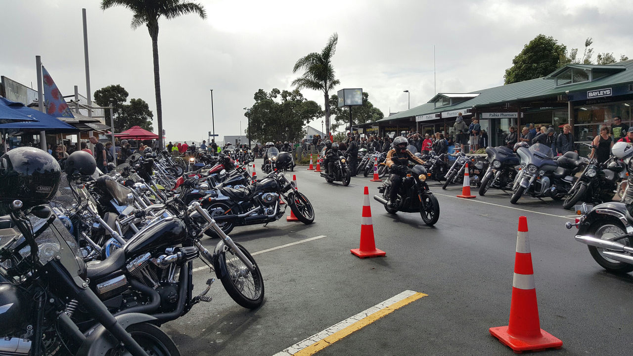 Man traveling amidst parked motorcycles on road in city